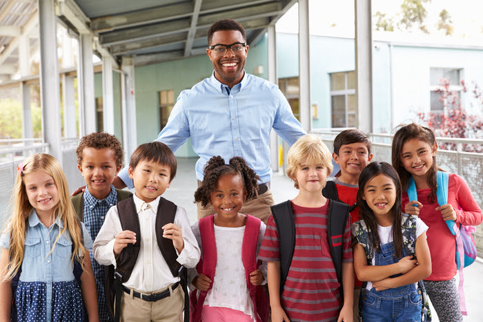 Portrait of elementary school kids and teacher in corridor