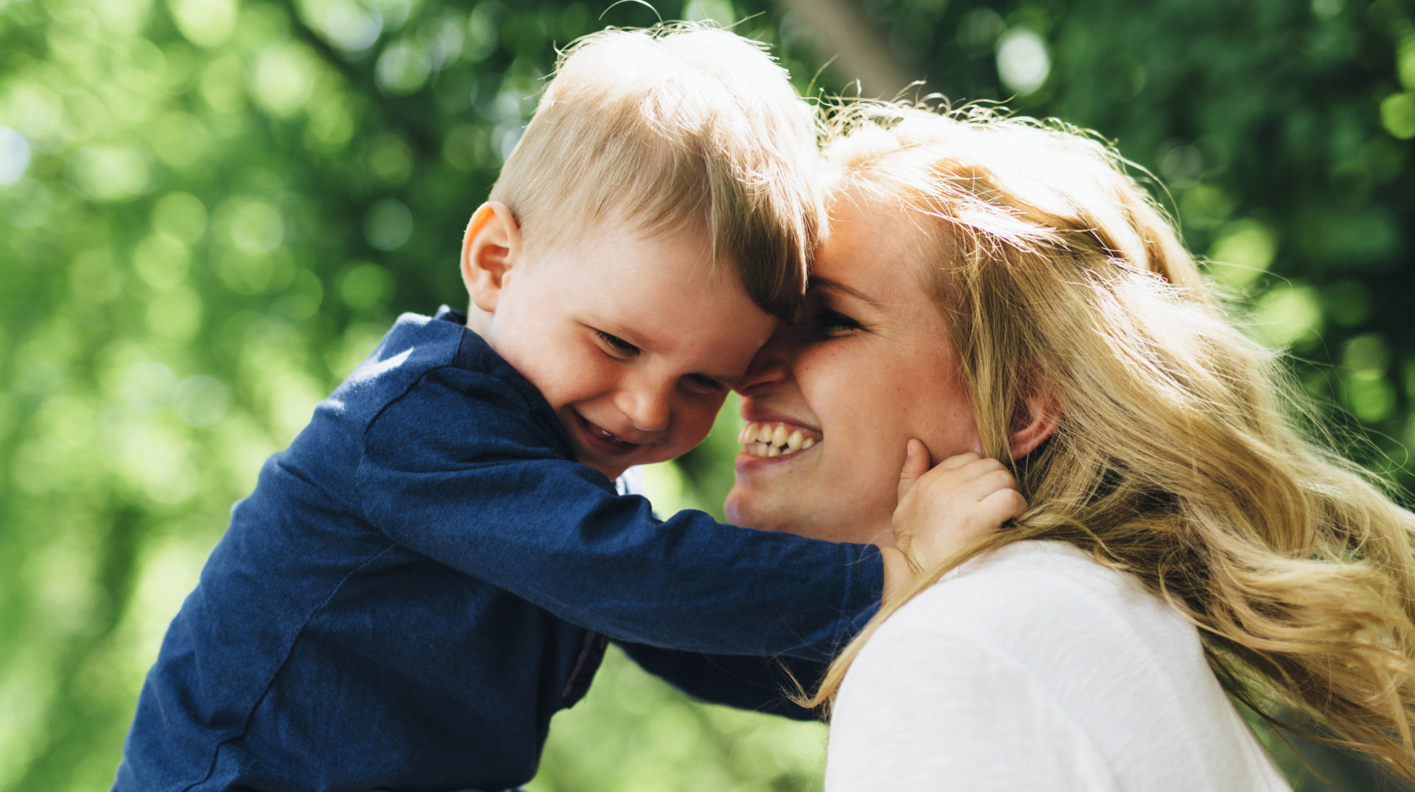 Mother smiling laughing and playing with her child outdoors on a nice summer day